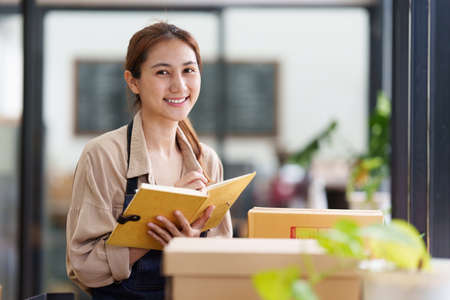 A portrait of Asian woman, e-commerce employee freelance with parcel box for deliver to customer. Online marketing packing box delivery concept.の写真素材