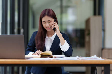Image of Happy Asian Business woman discussing with her business partner by cell phone. Finance and brainstorm concept.の写真素材