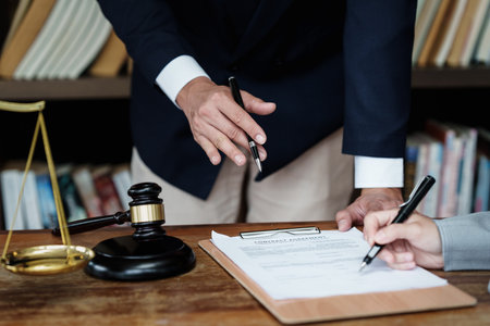 Business woman and lawyers discussing contract papers with brass scale on wooden desk in office....