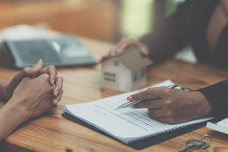 Close up Business woman or Real Estate agent giving house key after signing agreement for buying...