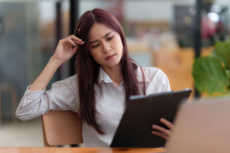 Image of Young woman stressed while reading a book for exam at library at school. back to school...