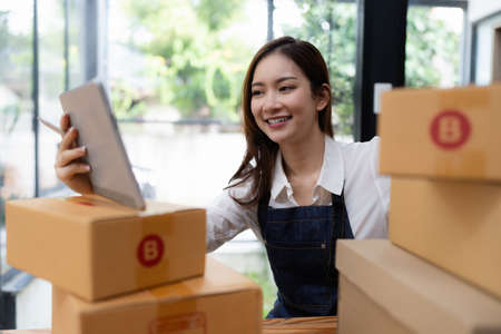 Attractive Asian entrepreneur business woman checking order by tablet