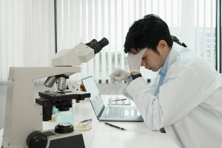 Stressed male scientist and hard working at laboratoryの写真素材