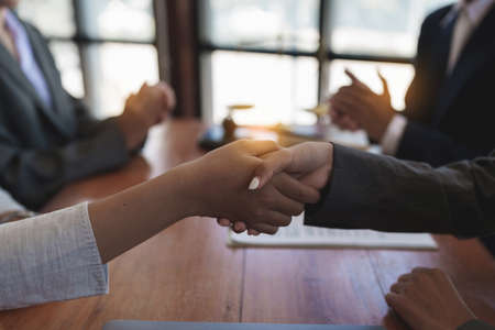Business team and lawyer shaking hand after discussing about agreement contract. Law, legal...