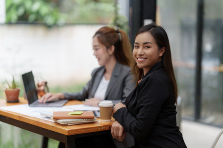 Positive Asian secretary smiling to camera during meeting at officeの写真素材