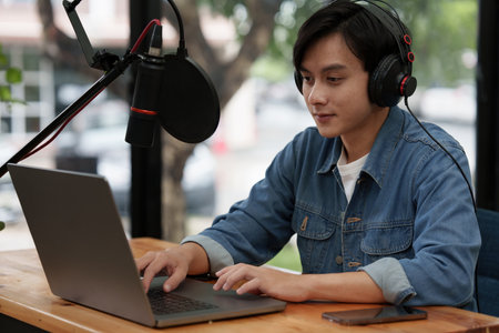 Asian podcaster editing audio podcast working at home studioの写真素材