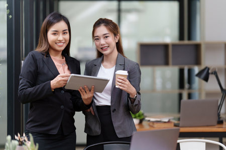 Two Positive Asian secretary smiling to camera during meeting at office.