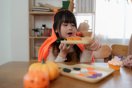 Young girl and mother at Halloween making treats and cupcake on table. Happy Halloween dayの写真素材