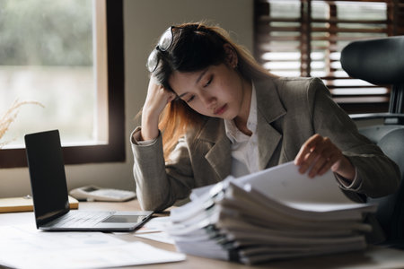 Stressed Asian business woman worry with many document on desk at officeの写真素材