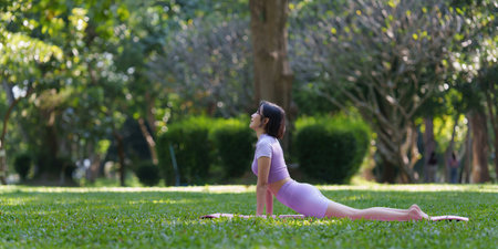 Attractive Asian female in sportswear practicing yoga in the outdoor park