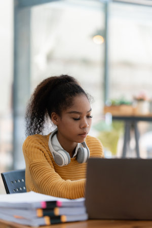 Portrait of beautiful young black woman using laptop at cafeの写真素材