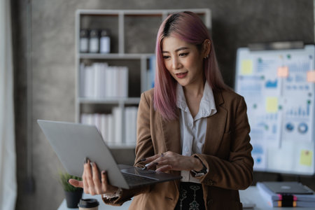 Asian Business woman working to analyze technical price graph and indicator with business team talking by cell phone. account or saving money or insurance conceptの写真素材