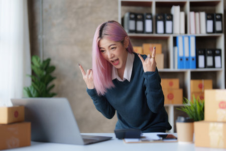 Startup small business entrepreneur of freelance Asian woman using a laptop with box Cheerful success online marketing packaging box and delivery SME idea conceptの写真素材