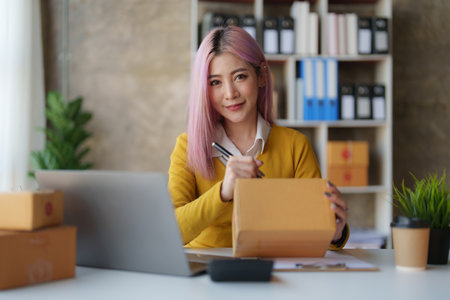 Startup small business entrepreneur of freelance Asian woman using a laptop with box Cheerful success online marketing packaging box and delivery SME idea conceptの写真素材