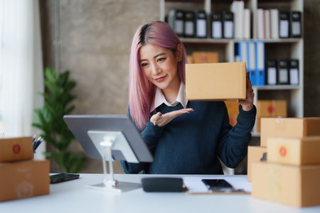 Startup small business entrepreneur of freelance Asian woman using a laptop with box Cheerful success online marketing packaging box and delivery SME idea conceptの写真素材