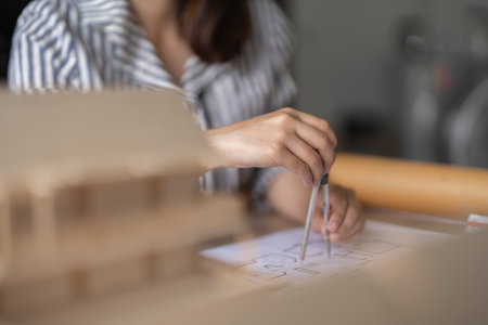 Architect woman working with blueprints for architectural plan, engineer sketching a construction project, green energy conceptの写真素材