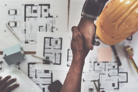 Architect and engineer construction workers shaking hands after finish an agreement in the office construction site, success collaboration conceptの写真素材