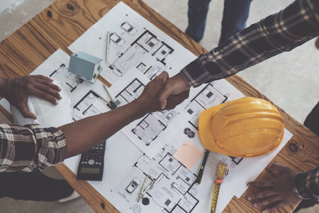 Architect and engineer construction workers shaking hands after finish an agreement in the office construction site, success collaboration conceptの写真素材