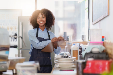 Young Female manager in restaurant with notebook. Woman coffee shop owner with open sign. Small business conceptの写真素材