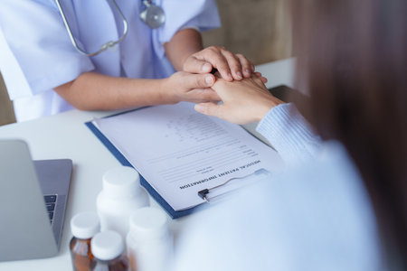 Doctor having conversation with patient while discussing explaining symptom and hold hand for encourageの写真素材
