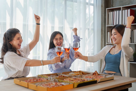 Friends at birthday party clinking glasses with champagne and pizza, enjoying Christmas vacation, pizza on the table. Holiday Party eventの写真素材