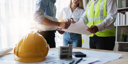 Architect team working with blueprints for architectural plan, engineer sketching a construction project, green energy conceptの写真素材