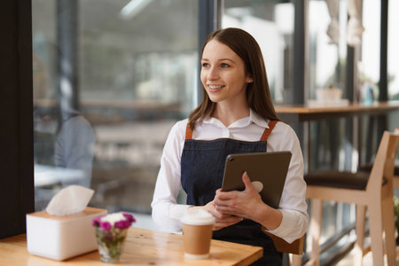 Young Female manager in restaurant with tablet. Woman coffee shop owner with open sign. Small business conceptの写真素材