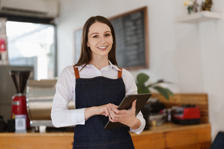 Young Female manager in restaurant with tablet. Woman coffee shop owner with open sign. Small business conceptの写真素材