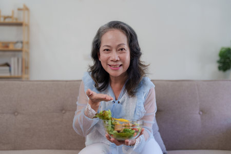 Happy old asian woman eating fresh green salad. Senior woman good healthy at home. Exercise and healthy diet conceptの写真素材