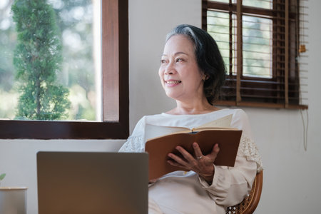 Smart asian mature middle-aged businesswoman CEO boss leader teacher using laptop, e-learning , working remotely online in home officeの写真素材