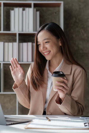 Smiling asian business woman with laptop computer in office. Woman in suit at officeの写真素材