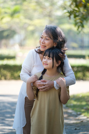 Asian Grandmother and Granddaughter hug together outdoor park. Hobbies and leisure, lifestyle, family life, happiness moment conceptの写真素材