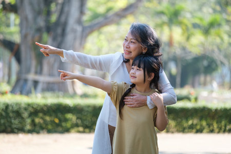 Asian Grandmother and Granddaughter hug together outdoor park. Hobbies and leisure, lifestyle, family life, happiness moment conceptの写真素材