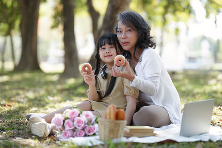 Asian Grandmother and Granddaughter having activity together outdoor park. Hobbies and leisure, lifestyle, family life, happiness moment conceptの写真素材