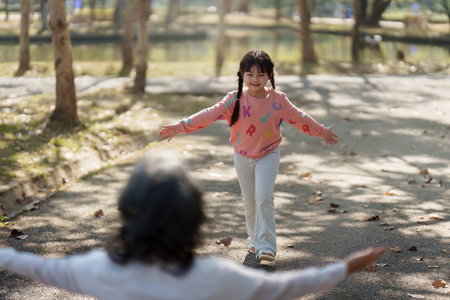 Asian Grandmother and Granddaughter hug together outdoor park. Hobbies and leisure, lifestyle, family life, happiness moment conceptの写真素材