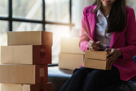 Beautiful Asian young woman SME working with a box at home. small business owner entrepreneur SME and delivery conceptの写真素材