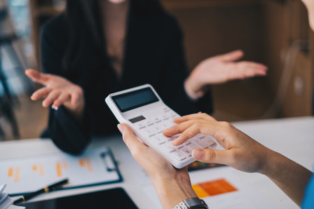 Asian Business Woman or Accountant do math and analyze with calculator and paperwork on desk, account, consult, audit and saving concept.の写真素材