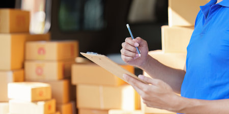 Asian courier with parcel and delivery logistic concept. Delivery man with checking list on clipboardの写真素材