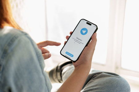 CHIANG MAI, THAILAND, FEB 12, 2023 : Woman hand using iPhone 14 with social networking service Telegram on the screen. Close up woman holding iPhoneのeditorial素材