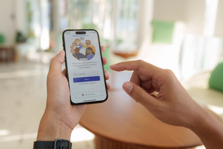 CHIANG MAI, THAILAND - FEB 12, 2023 : A Man working from home employee using the Microsoft Teams application by iphone 14.のeditorial素材