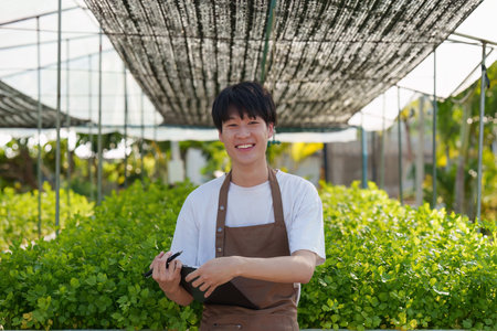 Portrait of farm owner smiling. Asian male business working at organic farm and quality control.の写真素材