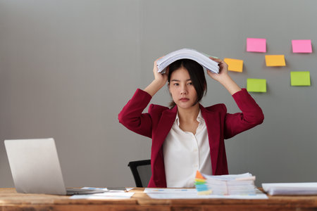 Tired business woman in stress works with many paperwork document. migraine attack. Freelance, work from homeの写真素材