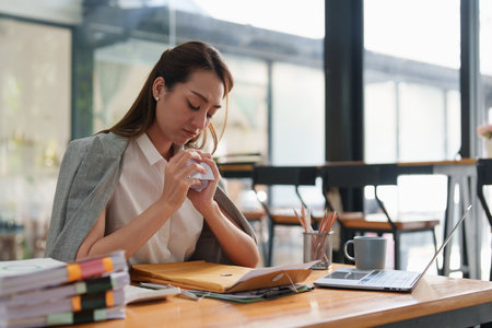 Tired business woman in stress works with many paperwork document. migraine attack. Freelance, work from home.の写真素材