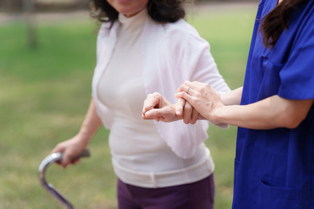 Healthcare nurse, physical therapy with elderly woman at outdoor. Nurse holding hand and help elderly woman walkingの写真素材