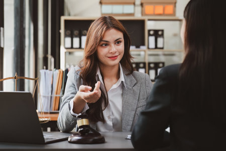 Business woman and lawyers discussing contract papers with brass scale on wooden desk in office. Law, legal services, advice, Justice and real estate conceptの写真素材