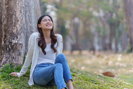 Cheerful overjoyed woman happy and enjoying peaceful beautiful in park, looking up with broad smileの写真素材