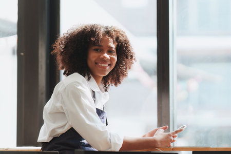 Beautiful American African cafe owner standing at cafe and using mobile phone. work in cafe, restaurantの写真素材