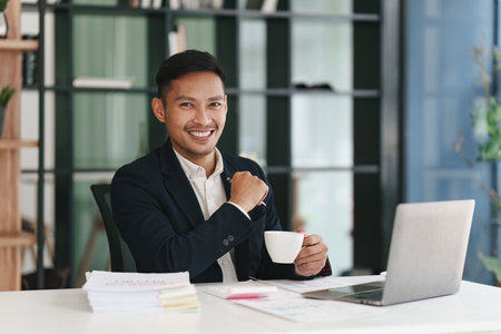 Smiling Asian Banker makes financial report and studies annual figures, analyzes profits. Accountant checks status of financialの写真素材