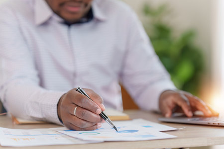 Smiling American African makes financial report and studies annual figures, analyzes profits. Accountant checks status of financialの写真素材