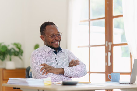 Smiling American African makes financial report and studies annual figures, analyzes profits. Accountant checks status of financialの写真素材